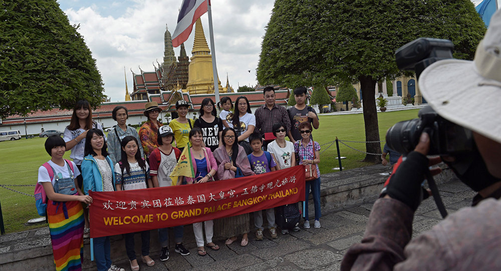 Chinese tourists pose for a group picture before visiting the Grand Palace in Bangkok